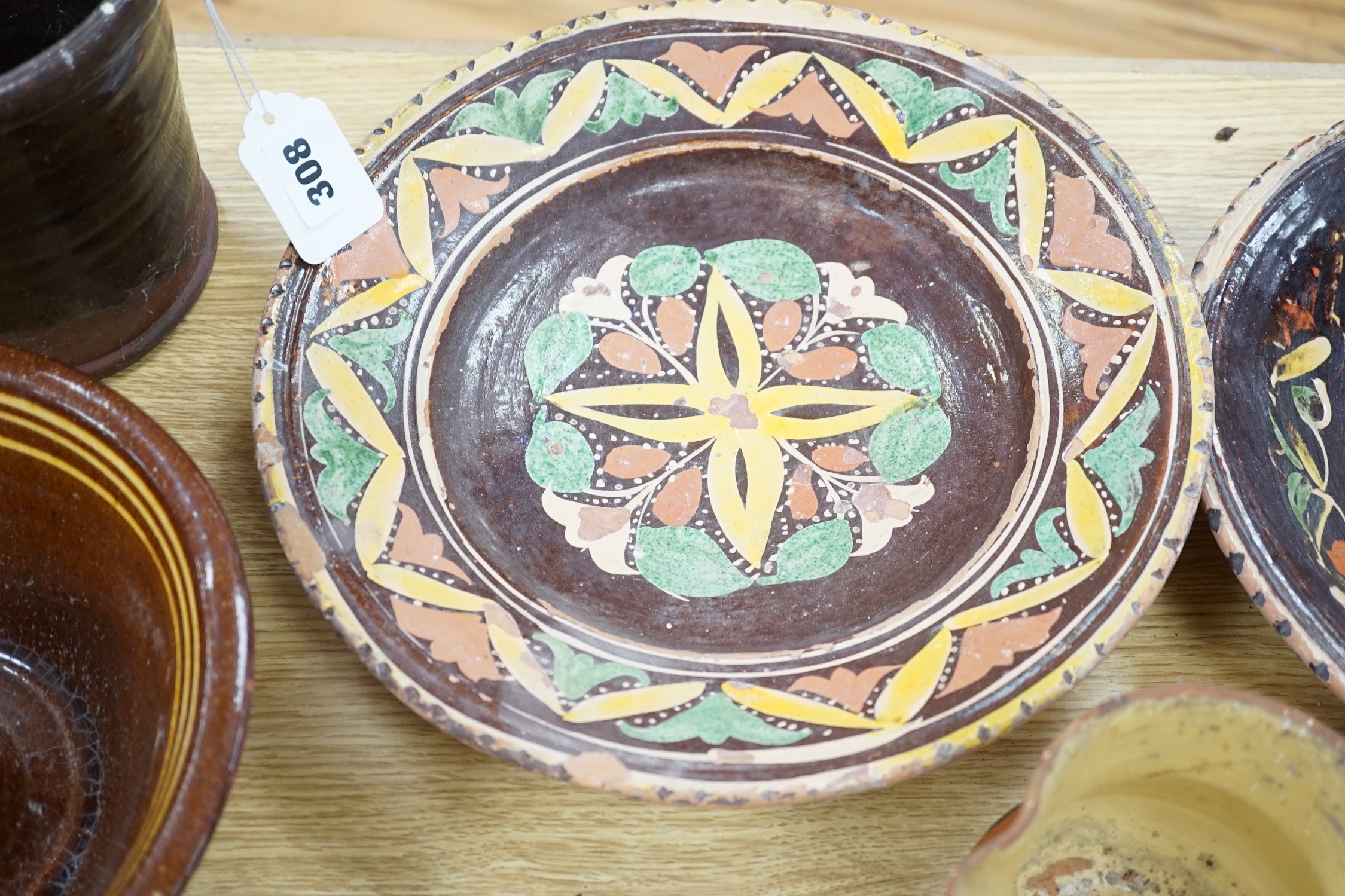 A group of Mediterranean slipware dishes, bowls and jugs, decorated in colours on a predominantly brown or ochre ground, the largest 33cm in diameter